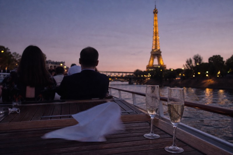 Glasses of Champagne on the deck of an evening Seine cruise with the Eiffel Tower lit behind