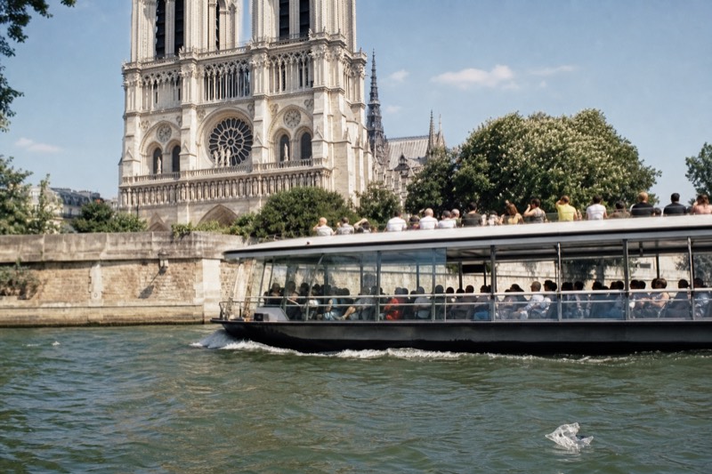 Sightseeing cruise boat passing Notre-Dame on the Seine in daylight