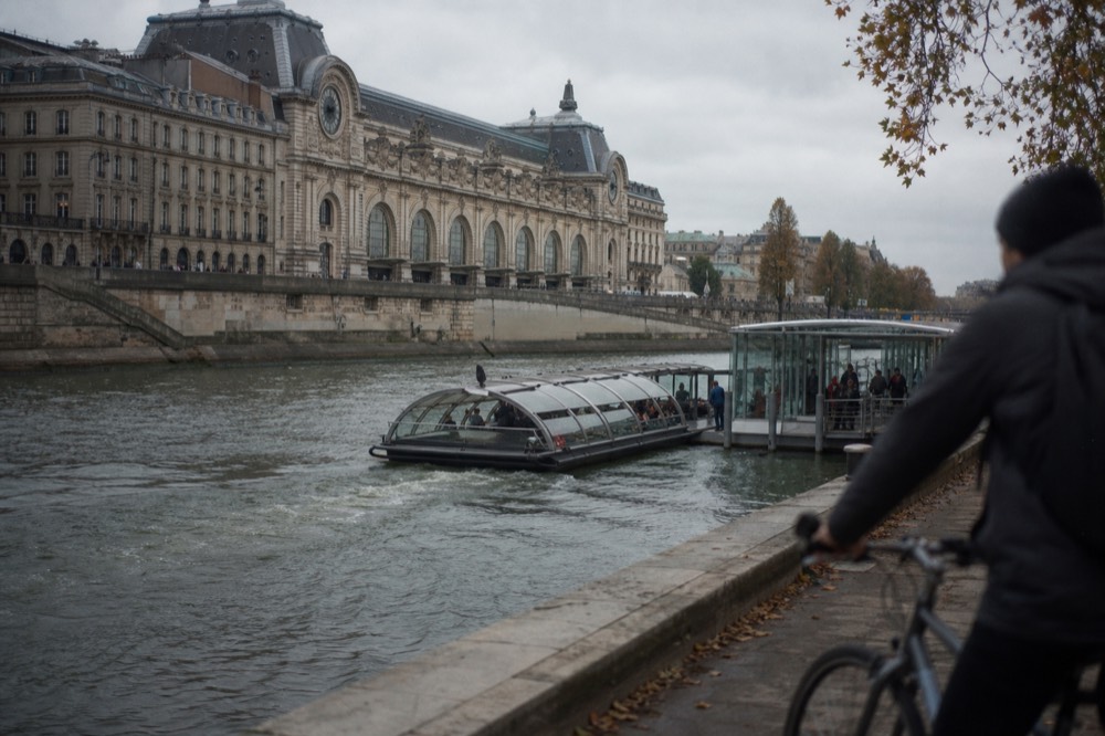 A Batobus shuttle boat approaching a glass-walled stop on the Seine, no text, no logos, no people