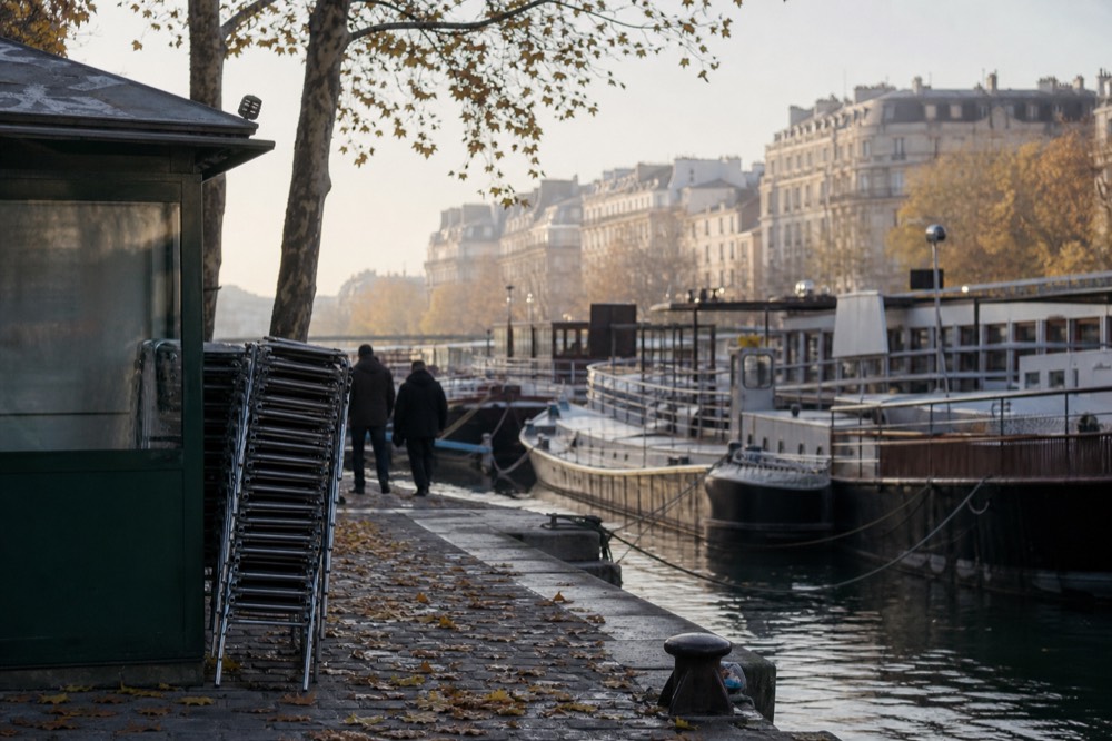 Tour boats moored along a Seine quay with Haussmann buildings behind, no text, no logos, no people