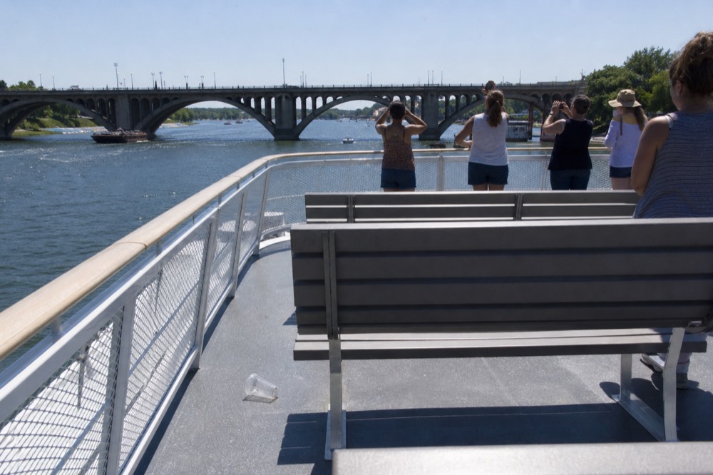 Upper open deck of a Seine excursion boat with bridge arches ahead, no text, no logos, no people