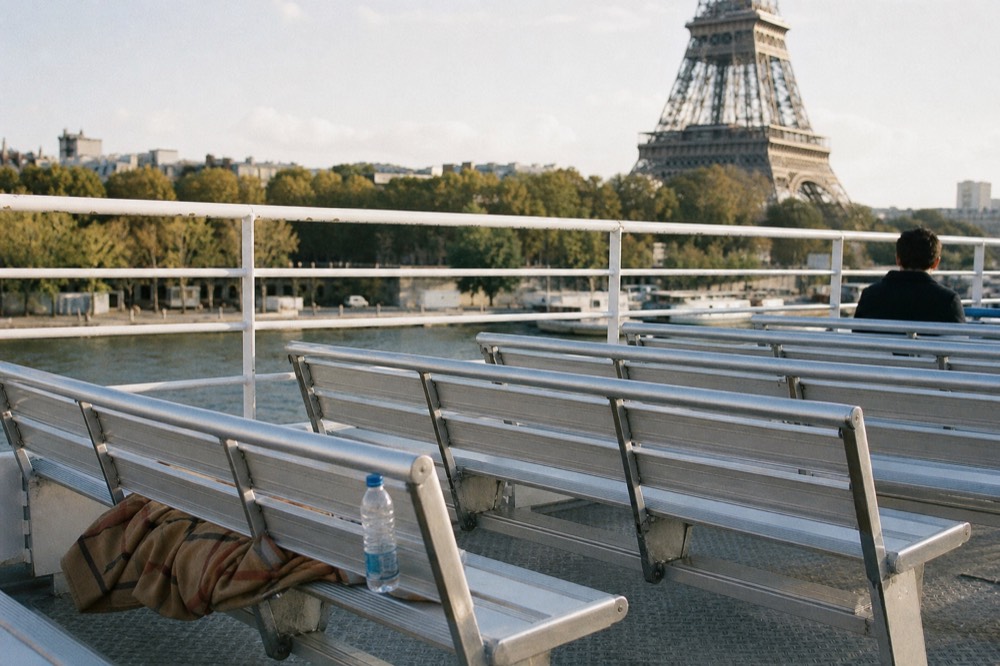 Open upper deck of a Seine cruise boat with the Eiffel Tower behind, no text, no logos, no people.