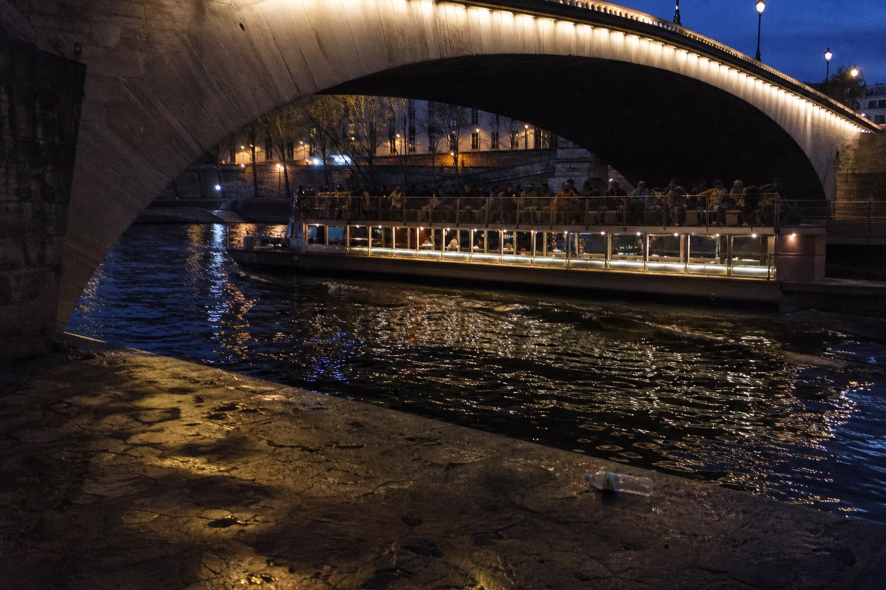A sightseeing boat passing illuminated bridges on the Seine at dusk, no text, no logos, no people.