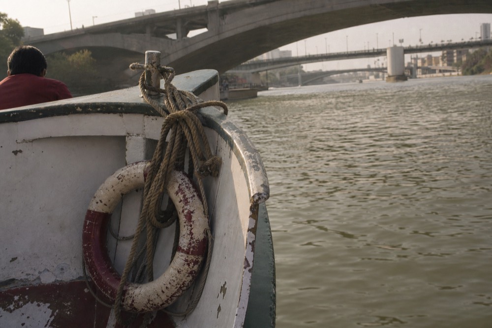 Close view of a passenger boat bow on the Seine with Parisian bridges behind, no text, no logos, no people