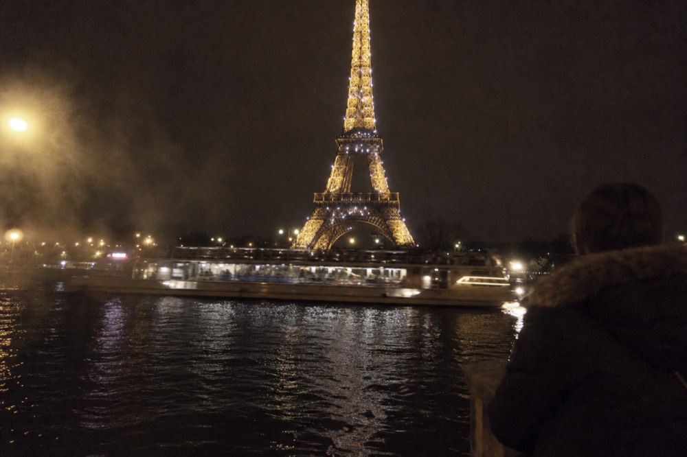 The Eiffel Tower sparkling at night above the Seine and a cruise boat, no text, no logos, no people
