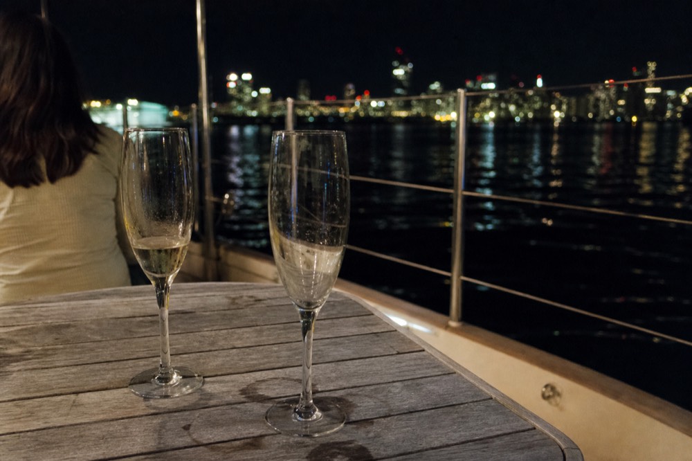 Champagne flutes on a boat table with city lights reflected on the Seine, no text, no logos, no people