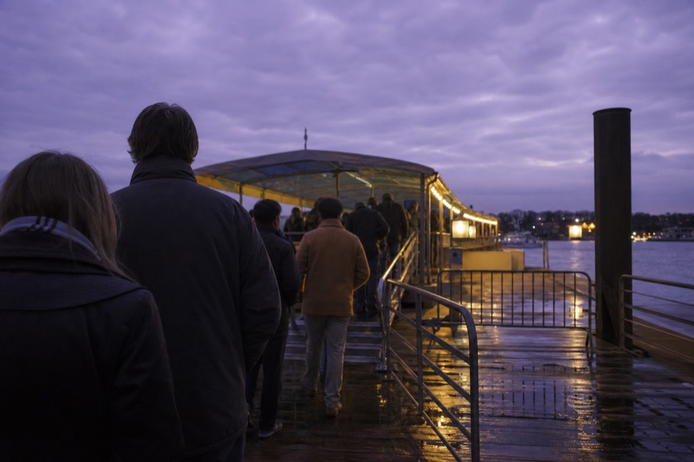 Passengers boarding an illuminated river boat at a Paris quay at dusk, no text, no logos, no people