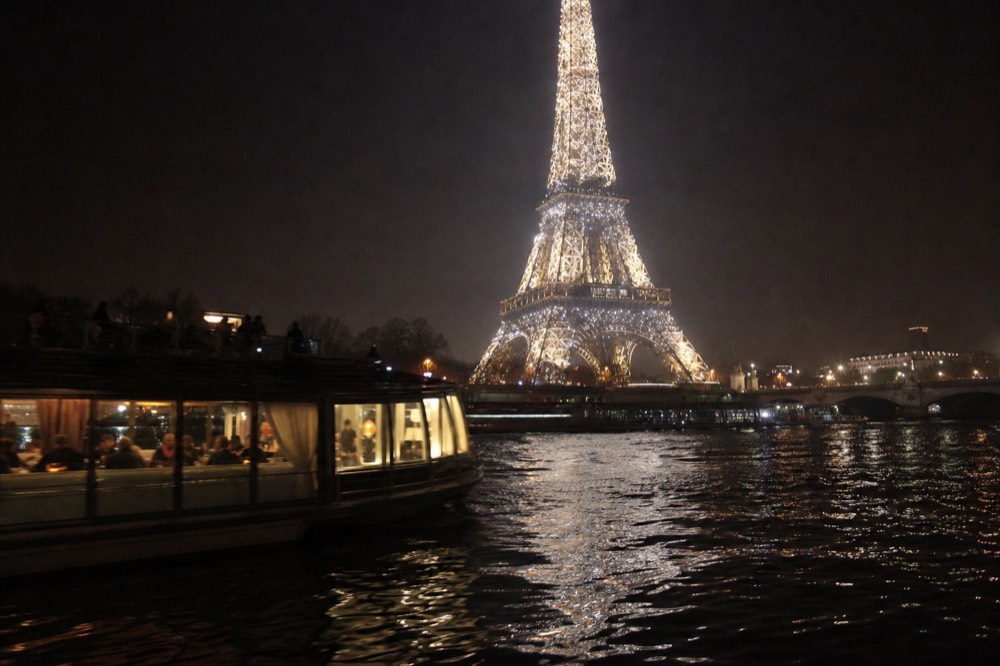 Evening dinner cruise passing the sparkling Eiffel Tower on the Seine, no text, no logos, no people