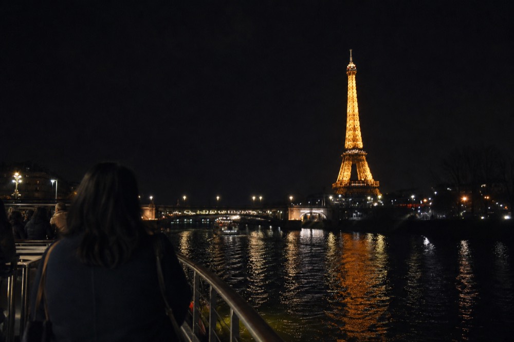 The illuminated Eiffel Tower from the Seine at night, no text, no logos, no people