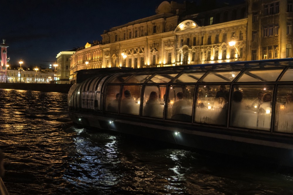 A dinner cruise boat gliding past illuminated Parisian architecture at night, no text, no logos, no people