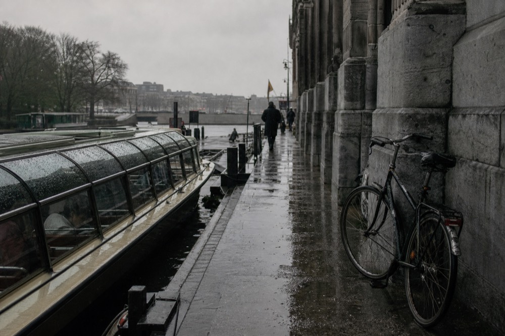 A glass-enclosed shuttle boat docked at a Seine stop beside a historic stone quay, no text, no logos, no people