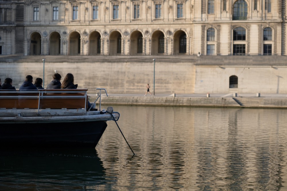 A sightseeing boat on the Seine in soft morning light near the Louvre, no text, no logos, no people