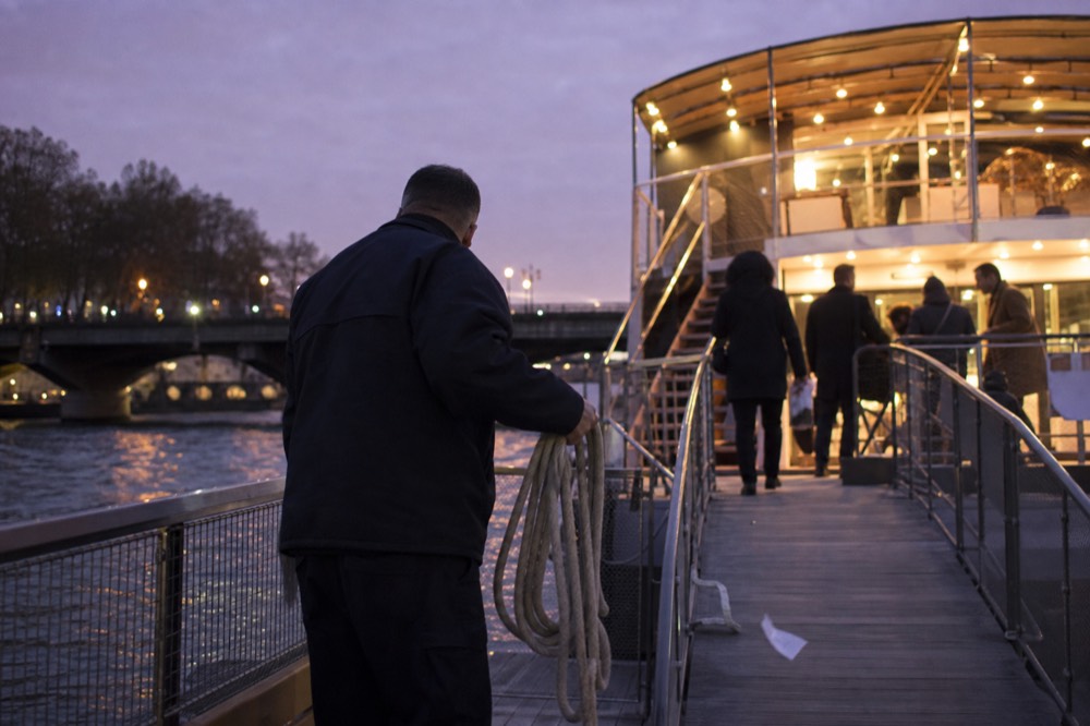 Passengers boarding a Seine cruise boat at an evening departure dock, no text, no logos, no people