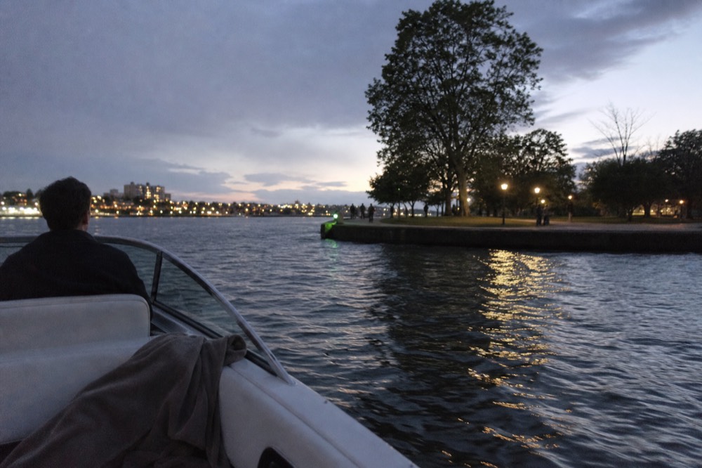 A small private boat on the Seine at dusk with city lights reflecting on the water, no text, no logos, no people
