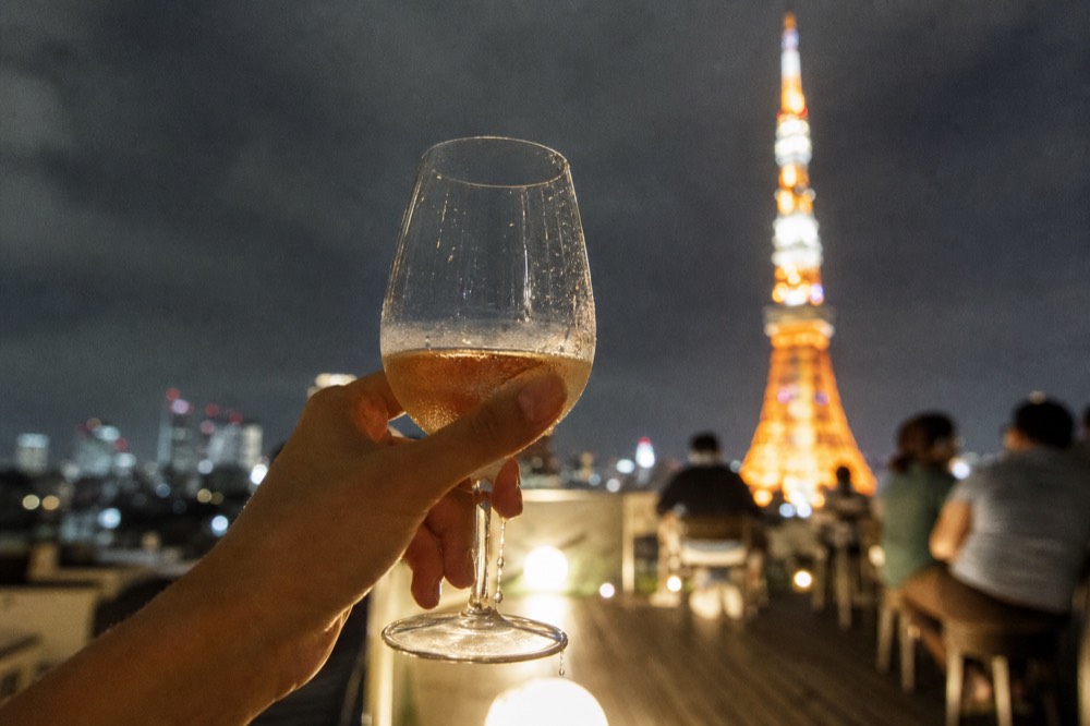 A glass of champagne held up against the illuminated Eiffel Tower from a boat deck, no text, no logos, no people