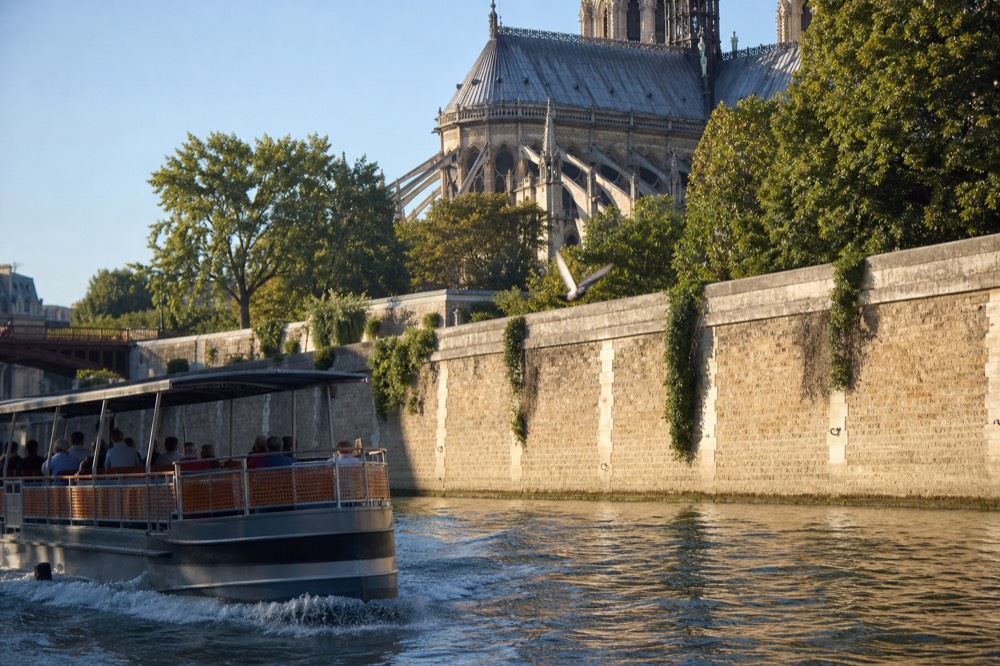 Passenger boat passing Notre-Dame Cathedral on the Seine with the Ile de la Cite quays, no text, no logos, no people