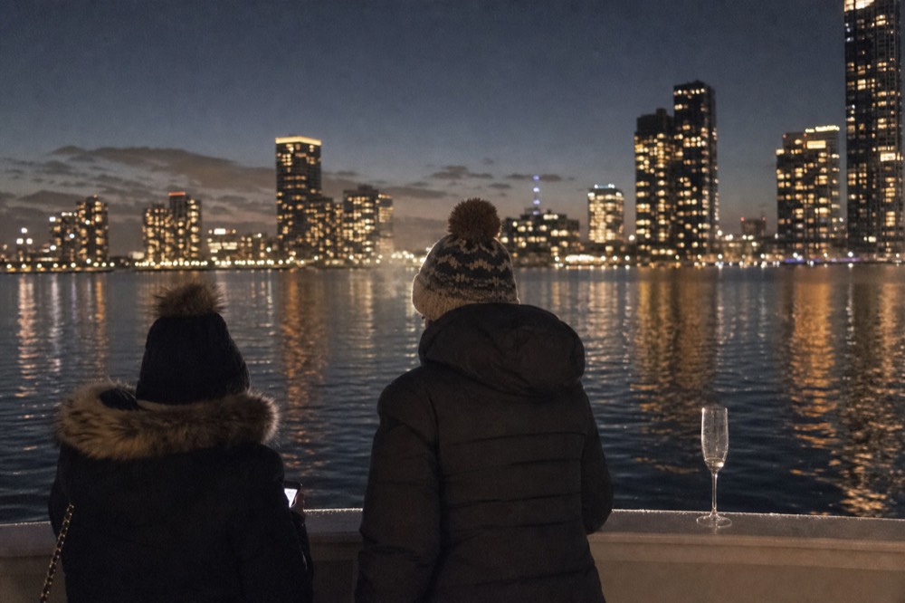 A couple at the railing of a Seine cruise boat at dusk with city lights reflecting on the water, no text, no logos, no people