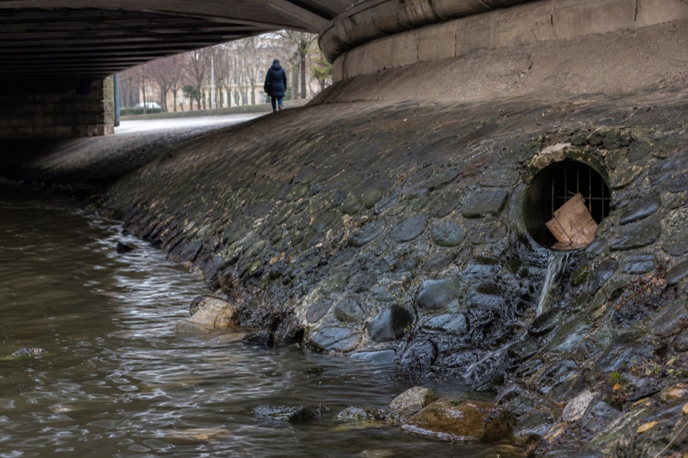 Stormwater outfall structure on the Seine embankment after rain, no text, no logos, no people