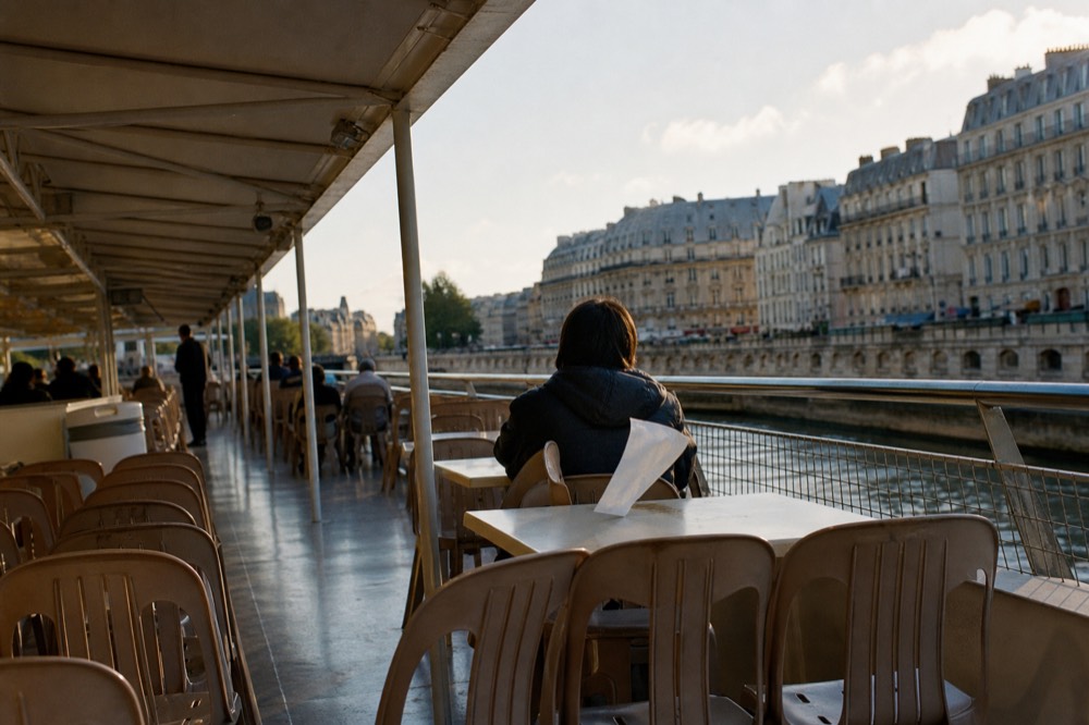 Open upper deck of a sightseeing boat cruising past Haussmann buildings along the Seine, no text, no logos, no people