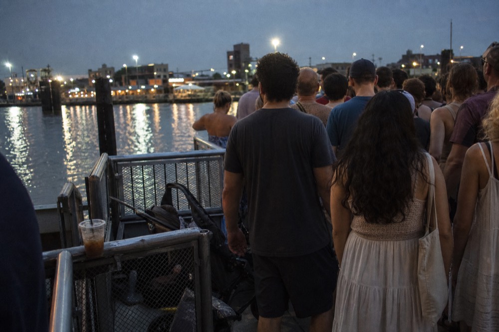 A crowd of visitors waiting on a Seine boarding pontoon, no text, no logos, no people