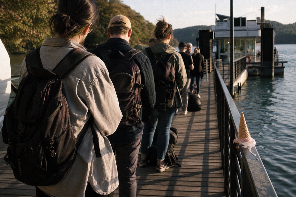 Queue of visitors waiting at a Seine boarding pontoon in late afternoon light, no text, no logos, no people.