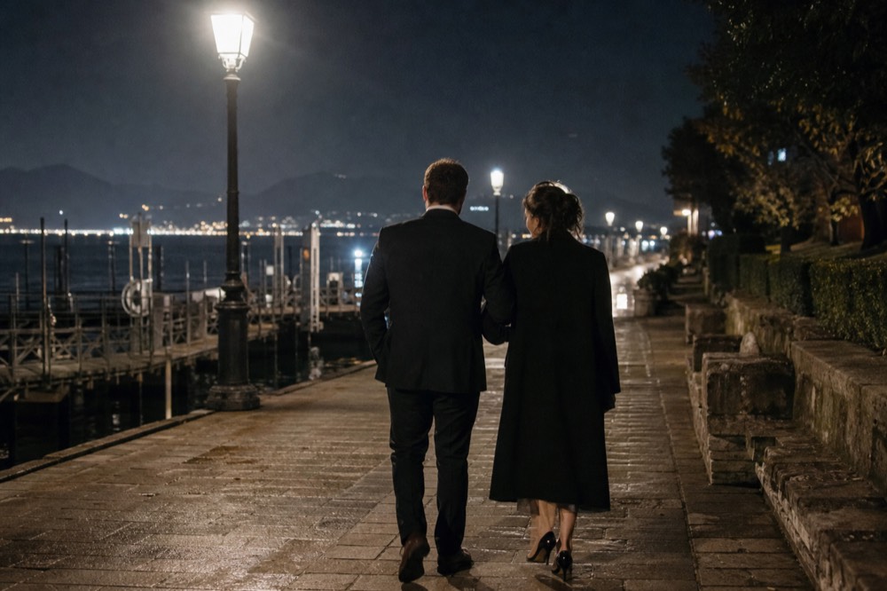 Elegantly dressed couple walking along a lit Paris quay toward a boarding dock at night, no text, no logos, no people